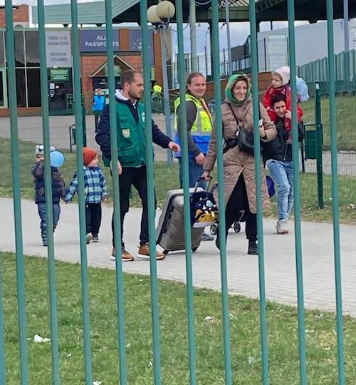A family arriving across the Polish-Ukrainian border, escorted by volunteers.